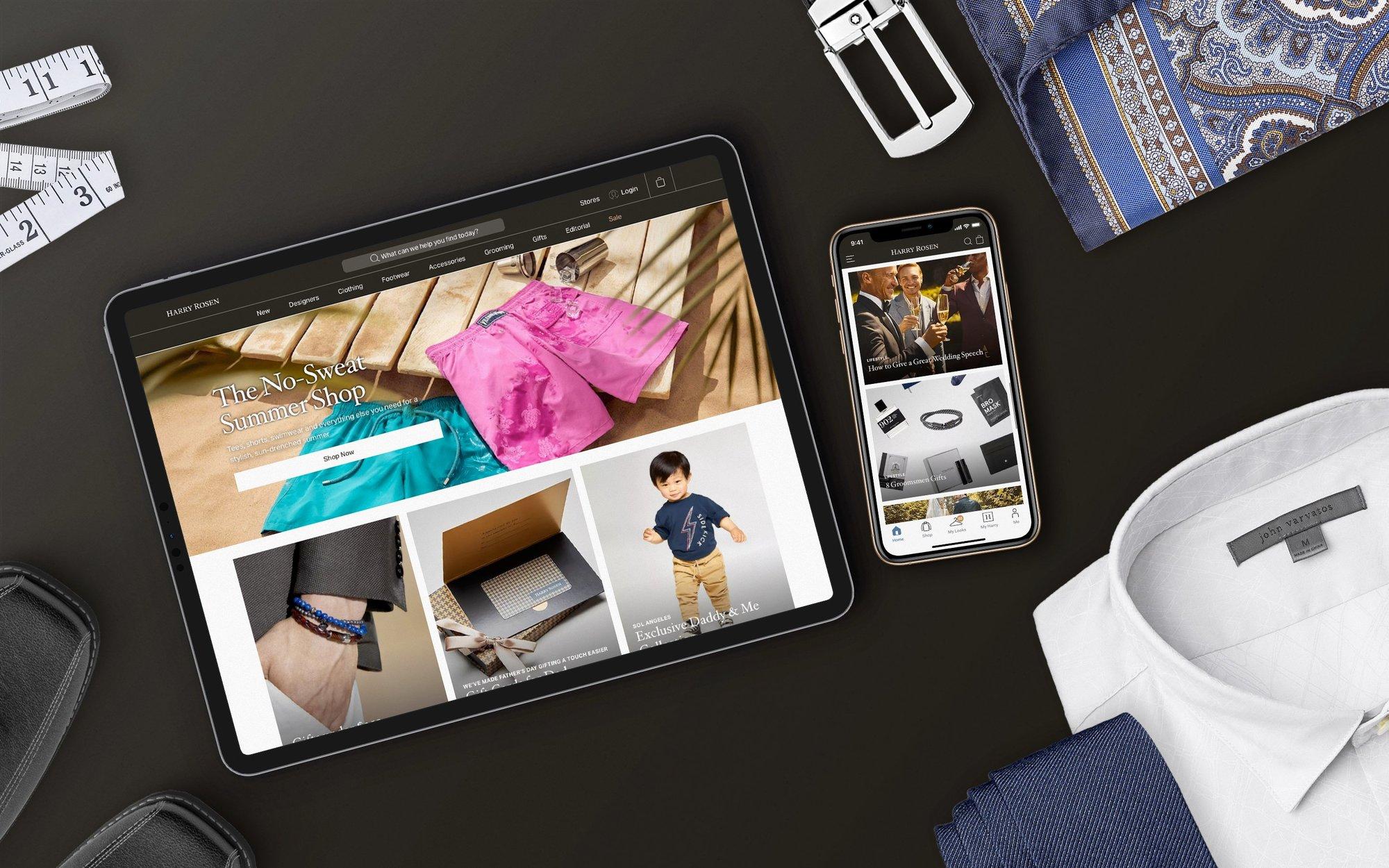 Photograph of tabletop with various menswear clothing items scattered around the edges with an iPad and iphone centered displaying the Harry Rosen website.